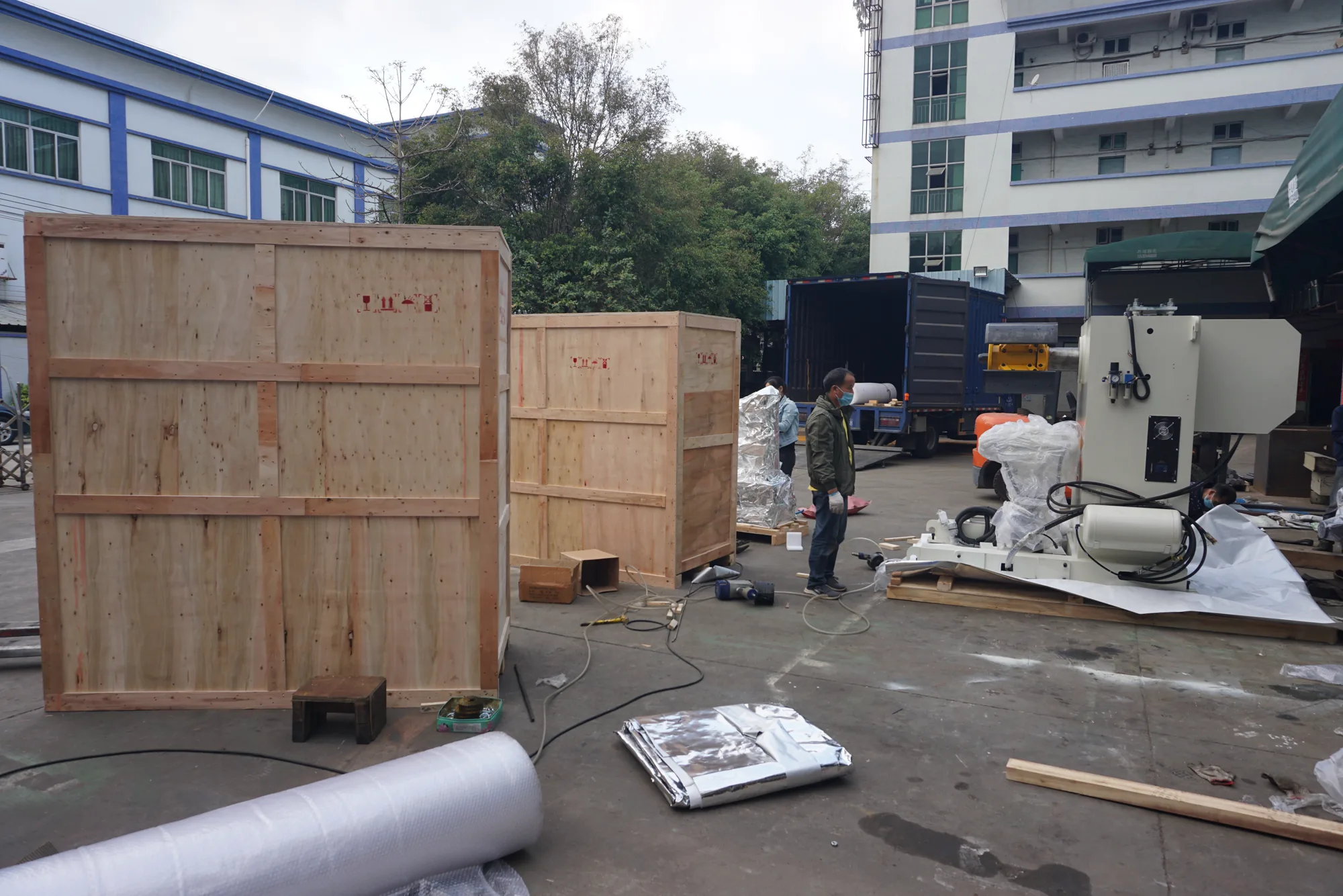 Cajas de exportación y maquinaria preparadas junto a un camión en el patio de envíos de HENLI